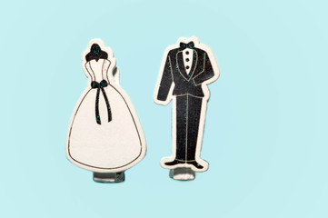 top view of decorative classic wedding dress and black groom tuxedo clips together isolated on blue surface with copy space, greeting concept