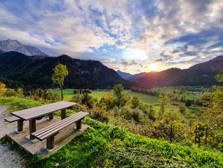 Golden morning sunbeams shine on a table overlooking green mountain landscape.