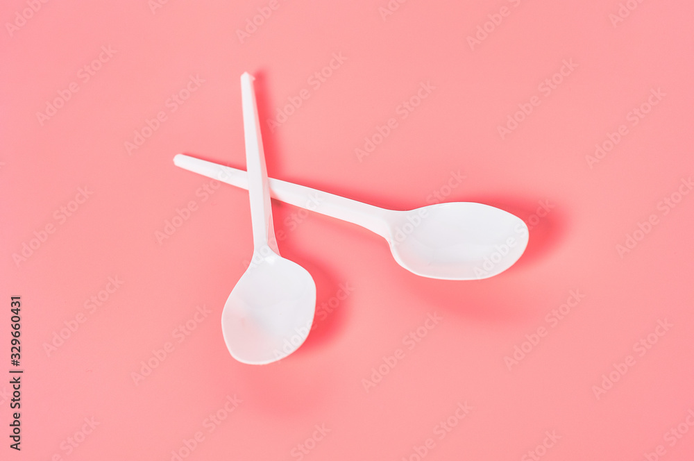 Wall mural two white disposable spoons scattered on pink background. concept of save environment, ecology, recr