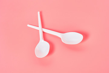 Two white disposable spoons scattered on pink background. Concept of save environment, ecology, recreation on picnic, party and other events
