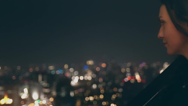 Pretty Woman Look Down Night Cityscape Rooftop. Panoramic Metropolis Observation at Midnight Blurred Lights. Business Dictrict Highrise Skyscrapers Location Nightlife Illumination Thailand Bangkok 4K