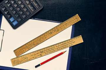 Education concept. Calculator and pencil over a sheet of paper and wooden rulers with maths...