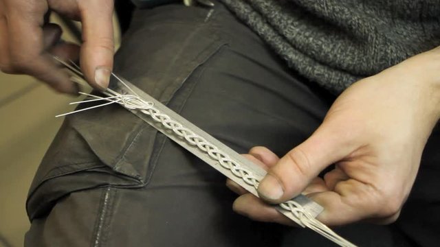 Close-up of weaving a silver bracelet, the hands of a master jeweler make a new product, selective focus