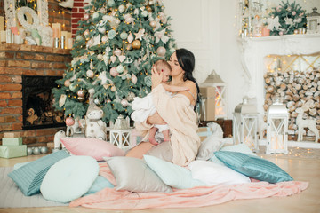 Baby girl and mother near Christmas tree