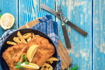 A piece of fried cod with fries on a plate.