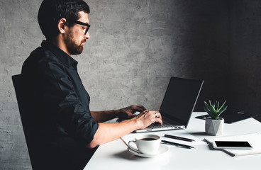 A man sits with a laptop in a black shirt. Business concept, work. Office routine. Property efforts