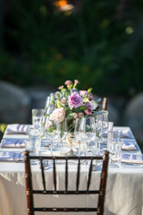 Table setting for a wedding ceremony with white tablecloth and crystal, decorated with flowers in vases
