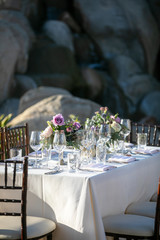 Table setting for a wedding ceremony with white tablecloth and crystal, decorated with flowers in vases