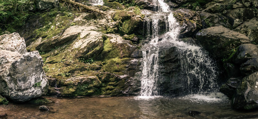 Panorama view of small waterfall situated in nature, water faling over rock © AllThings