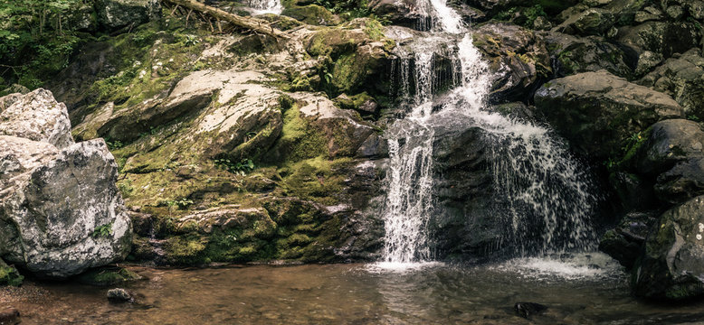 Panorama view of small waterfall situated in nature, water faling over rock