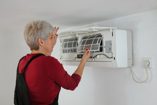 Female worker cleaning and repairing air condition equipment