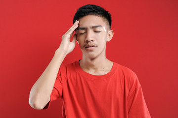 Young Asian man suffering from vertigo headache, A studio portrait of a painful Asian youth, holding his head