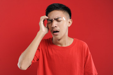 Young Asian man suffering from vertigo headache, A studio portrait of a painful Asian youth, holding his head