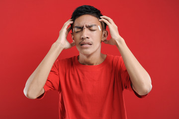 Young Asian man suffering from vertigo headache, A studio portrait of a painful Asian youth, holding his head