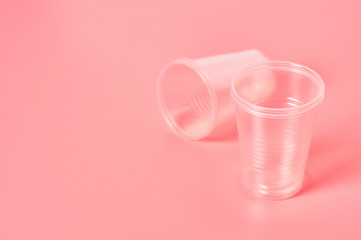 Disposable plastic glasses scattered on pink background. Concept of save environment, ecology, recreation on picnic, party and other events. Copy space