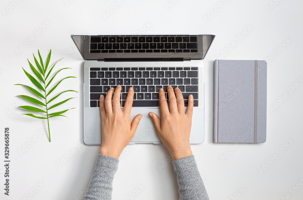 Poster person using a laptop computer with a notebook