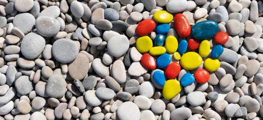 World autism awareness day. Top view to white beach stones with colorful heart made of painted stones