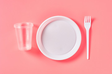 Disposable plastic utensils on pink background. Concept of save environment, ecology, recreation on...