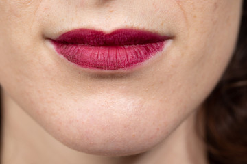 Close up view of nice sensual woman lips with red matt lipstick. Woman smiling. Cosmetology, drugstore and fashion makeup concept...