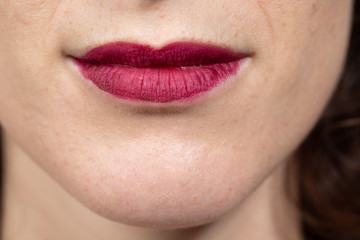 Fototapeta premium Close up view of nice sensual woman lips with red matt lipstick. Woman smiling. Cosmetology, drugstore and fashion makeup concept...