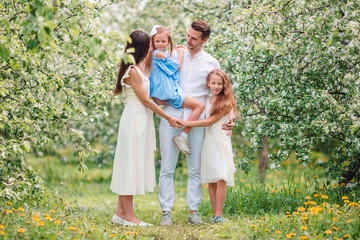 Fototapeta premium Adorable family in blooming cherry garden on beautiful spring day