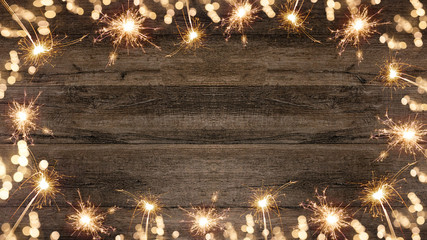Silvester festive background - Frame made of sparklers and bokeh lights on rustic wooden brown...