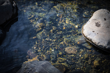 Fototapeta premium summer sunshine creates beautiful patterns on river stones under water