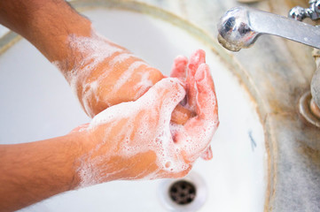 Indian person washing hands in a white coloured sink
