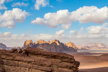Kingdom of Jordan, Wadi Rum desert, sunny winter day scenery landscape with white puffy clouds and warm colors. Lovely travel photography. Beautiful desert could be explored on safari. Colorful image