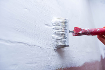 paint brush with a white paint primer - wall painting, apartment repair.