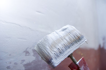 paint brush with a white paint primer - wall painting, apartment repair.