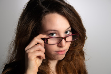Portrait of charming brunette woman holding her glasses in hand. Isolated on grey background...