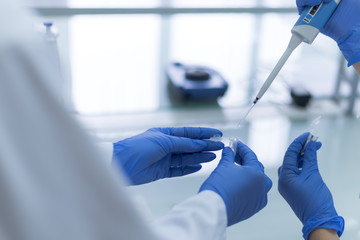 Group of Microbiologists with a tube of biological sample contaminated by Coronavirus with label Covid-19