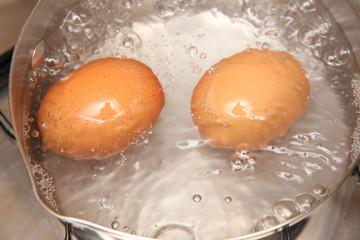 2 Eggs boiling on a hob in a pan of boiling water