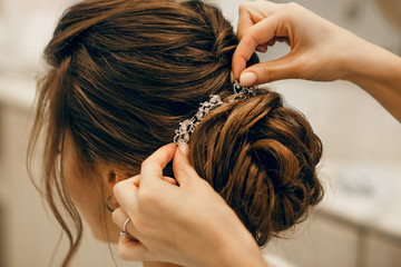 Naklejka premium The morning of the bride. Girl makes a stylish hairstyle, a friend helps the bride, a beautiful hair ornament, preparation for a party, close-up hairstyle