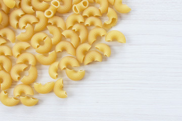 Italian short pasta, on white wooden background