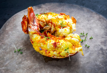 Traditional barbecue spiny lobster tail sliced and offered with saffron lemon sauce as closeup on a...