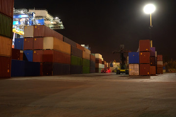 operation of container terminal at night. Unloading container ship at night. Mooring cranes unload...