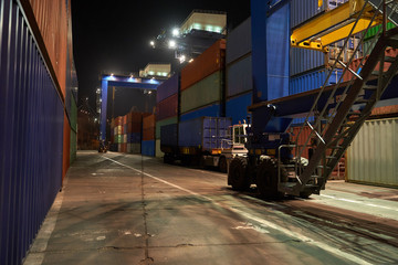 operation of container terminal at night. Unloading container ship at night. Mooring cranes unload container ship at night