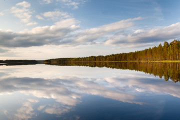 Beautiful volumetric clouds on a sunny day over a quiet forest lake
