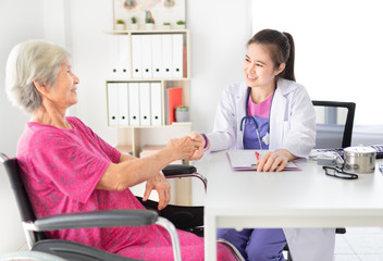 Fototapeta premium Asian doctor talk with old female patient about disease symptom, they holding hand together, elderly health check up, happiness hospital
