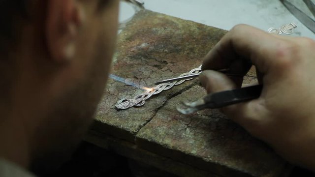Close-up master jeweler makes a silver bracelet, hand-made silver jewelry, selective focus