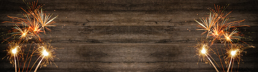 Silvester, festive background panorama long - Firework, sparklers and bokeh lights on rustic brown wooden texture with space for text	