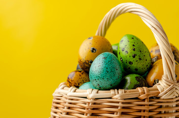 Easter eggs in basket on color wooden background copy