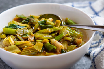 A bowl of vegetable soup, with scallions and celery.