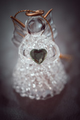 glass angel with heart on the dark brown vignette.