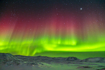 Spectacular red and green Aurora Borealis Northern Lights in Greenland © Alira Vale