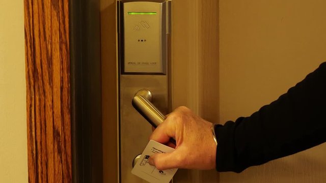 Womans hand uses hotel key card and door handle to enter the room, in close up clip.
