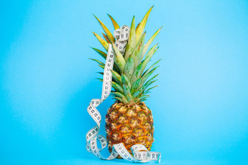 Ripe pineapple with measuring tape on a blue background