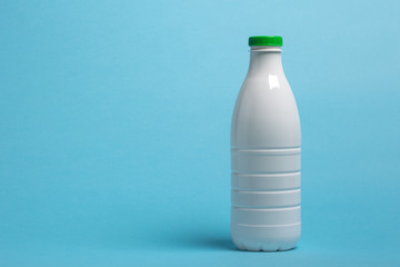 white plastic bottle for dairy products stands on blue background